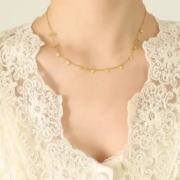 Woman's neck showing heart necklace, gold color